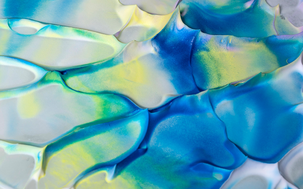 Abstract close-up of layered textured paint in blue, turquoise, white and soft yellow tones.