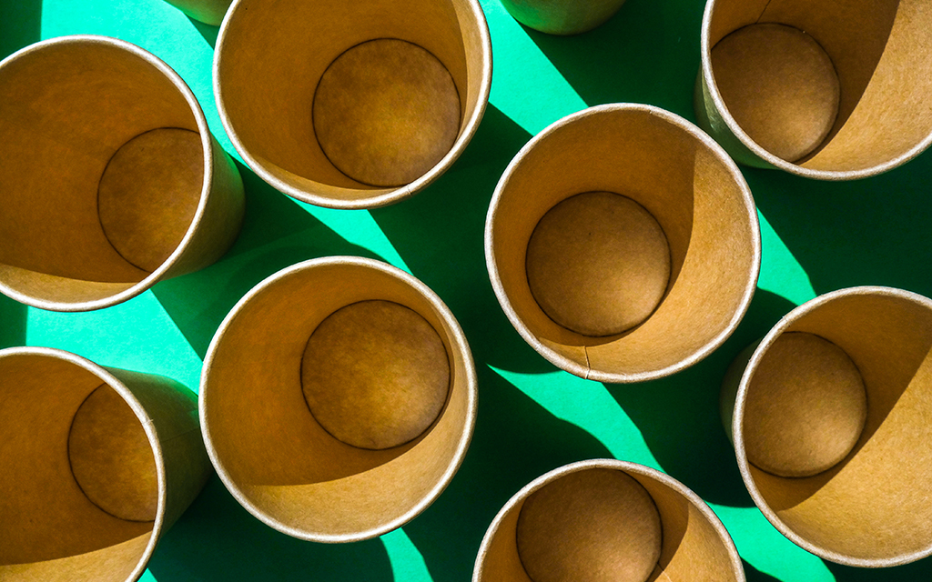 Set of recyclable cardboard cups on a green background