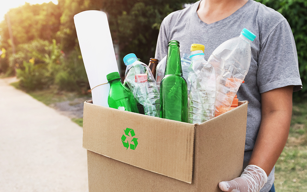 A woman's hand holding a box of recyclable waste